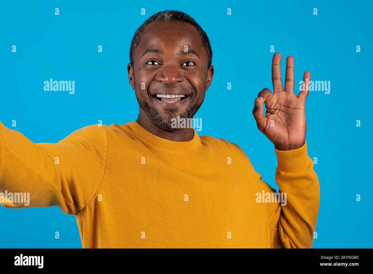Closeup of cheerful handsome black man taking selfie on blue Stock Photo
