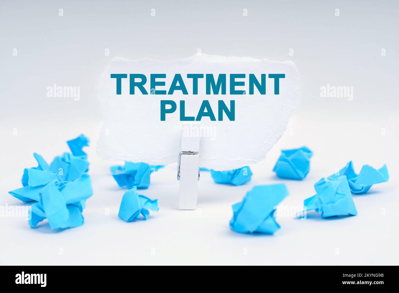 Medicine and health concept. On a white background, there are blue pieces of paper and a clothespin with paper on which it is written - TREATMENT PLAN Stock Photo