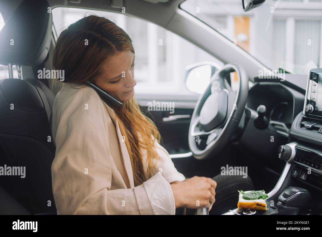 Female professional talking on smart phone while sitting in car Stock Photo