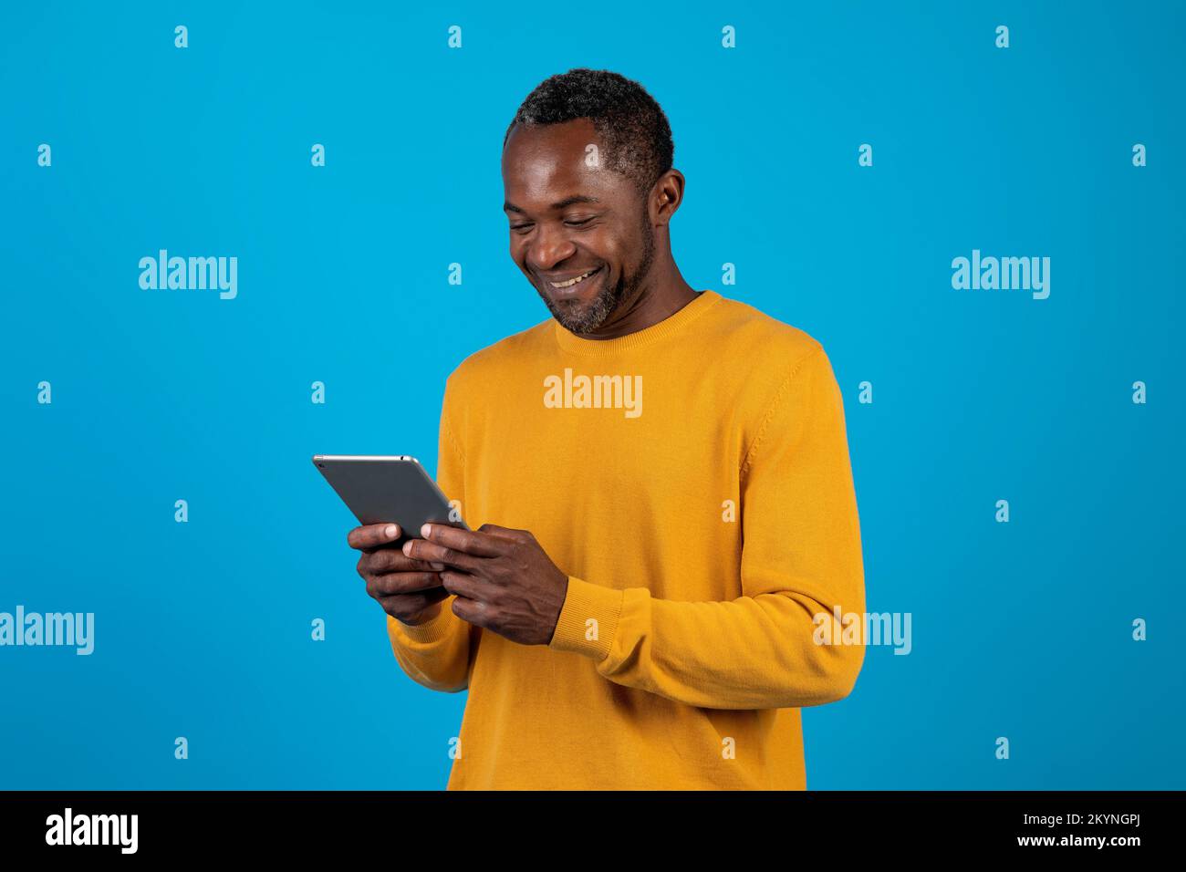 Happy african american man using digital tablet isolated on blue Stock Photo
