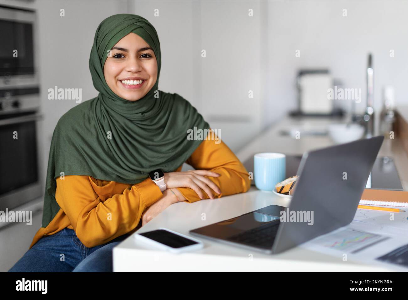 Freelance. Middle Eastern Woman In Hijab Sitting At Desk With With Laptop Stock Photo