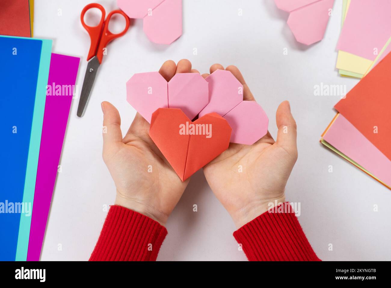 Making origami hearts for Valentine's Day. Crafts made of paper with your own hands. Stock Photo
