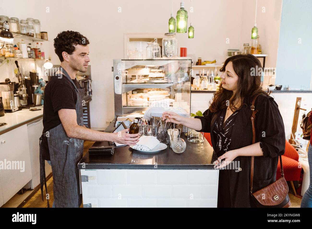 Female customer communicating with male cashier standing at checkout counter cafe Stock Photo