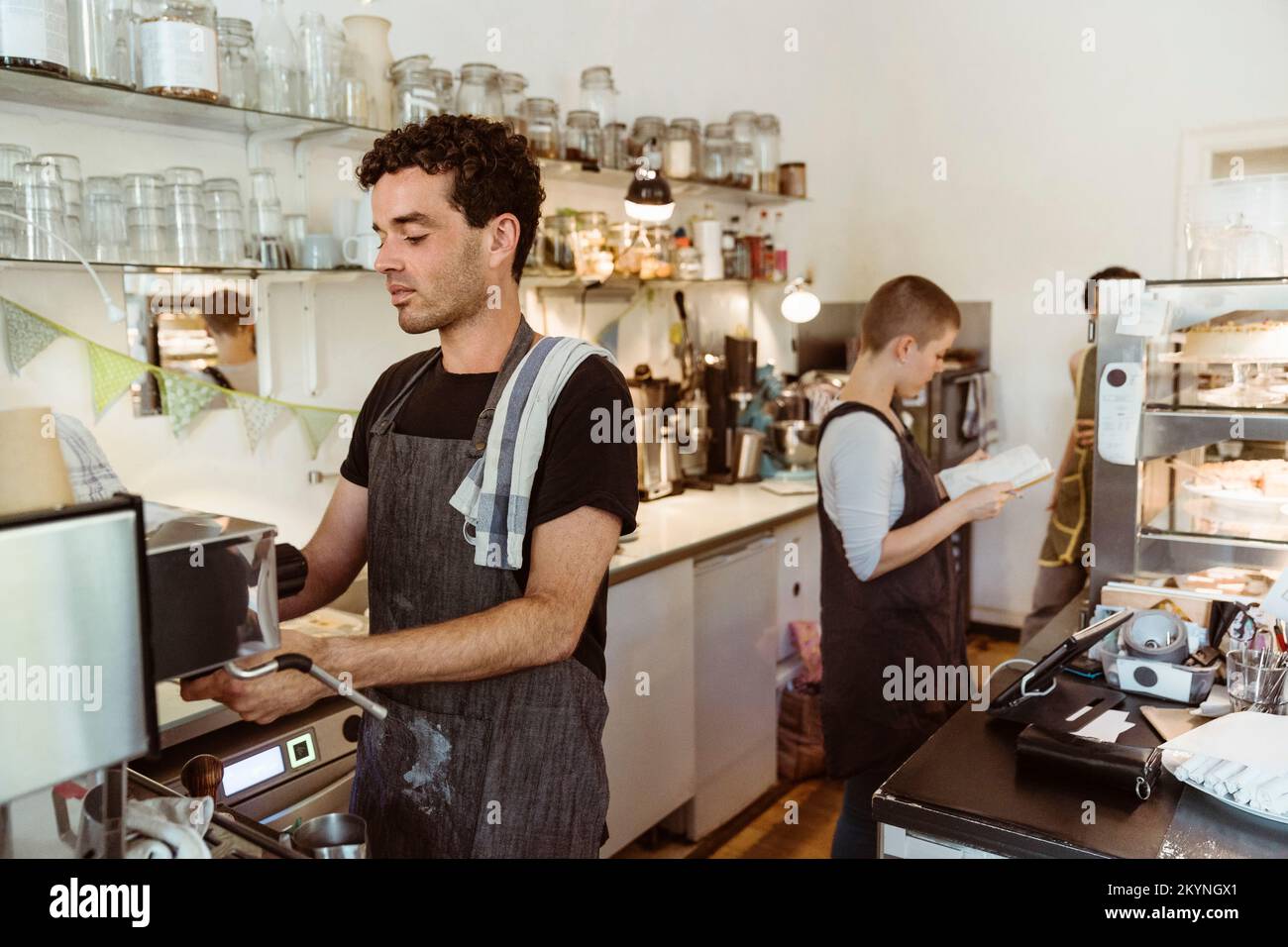 Male barista preparing coffee using coffee maker in cafe Stock Photo
