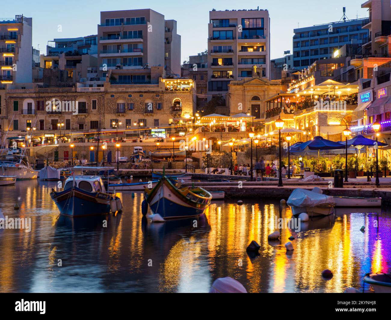 St Julian, Malta - May, 2021: Spinola bay with plenty of colorful boats in front of famous touristic restaurants during night time. Europe Stock Photo