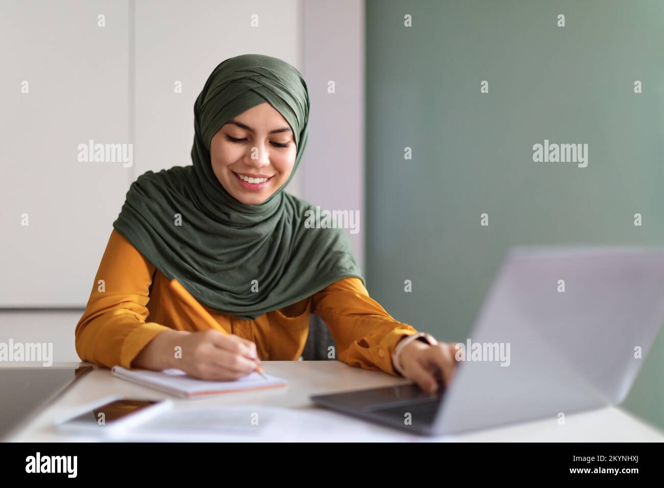 Online Education. Smiling Muslim Woman In Hijab Study With Laptop At Home Stock Photo