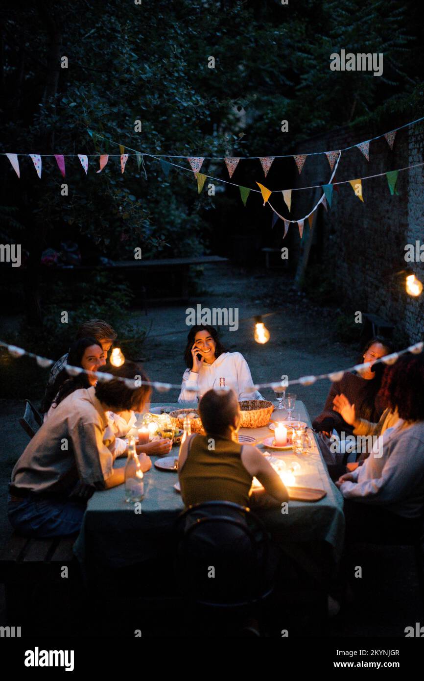 Friends enjoying dinner party in back yard decorated with bunting Stock Photo