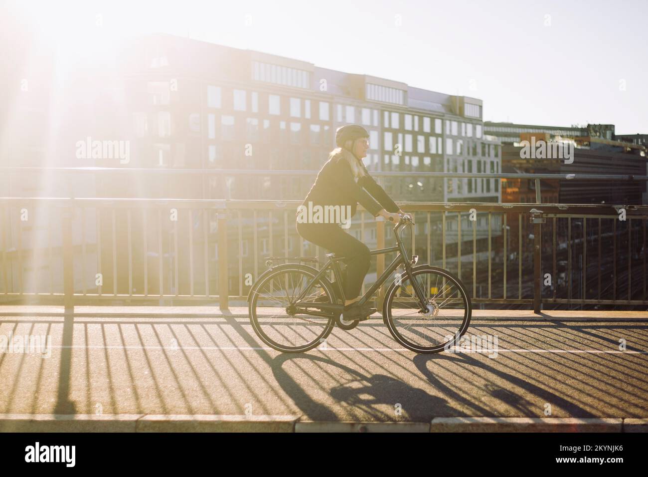 Businesswoman commuting through bicycle on road during sunny day Stock Photo