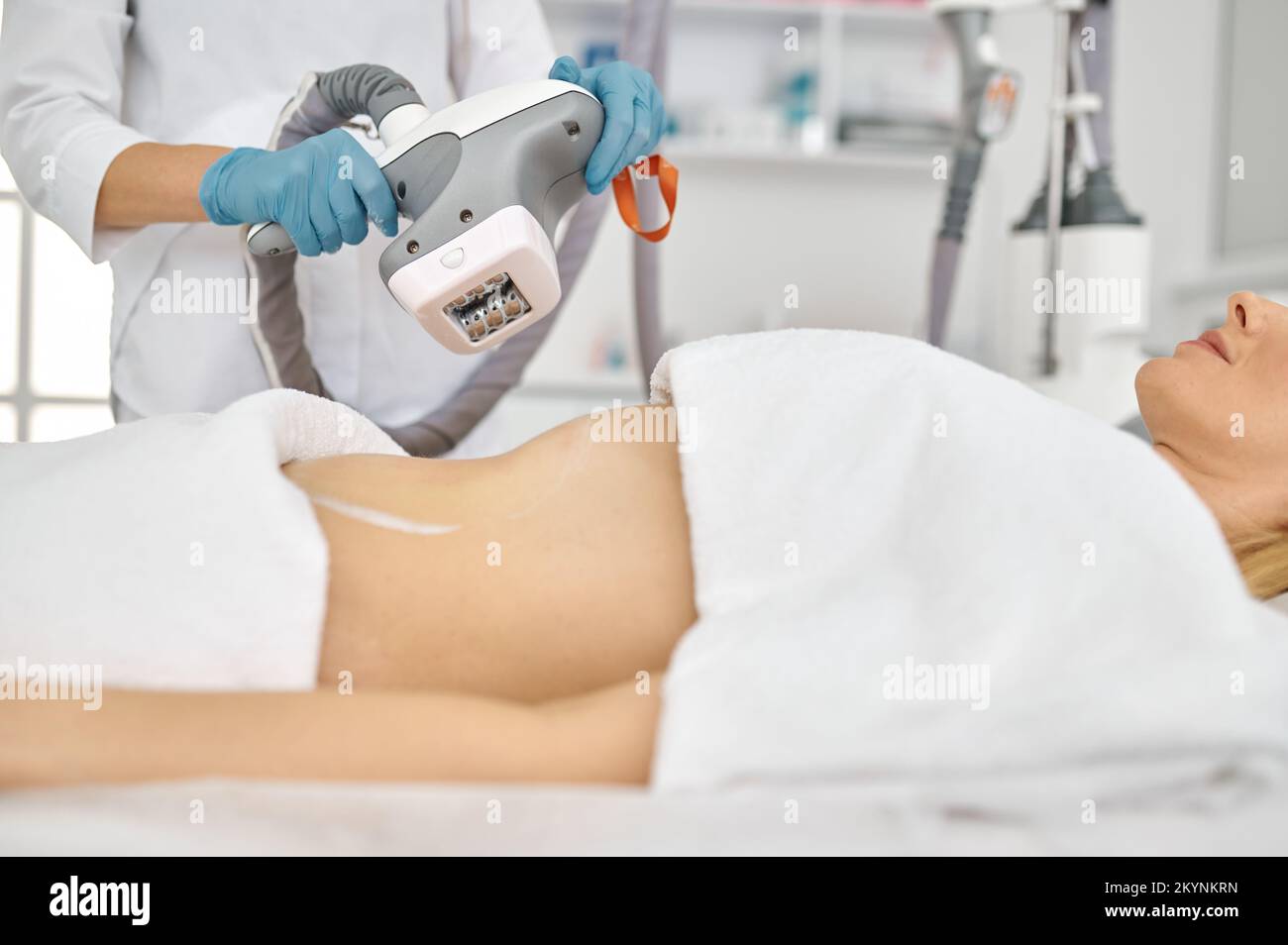 Doctor cosmetologist doing roller massage with apparatus closeup Stock Photo