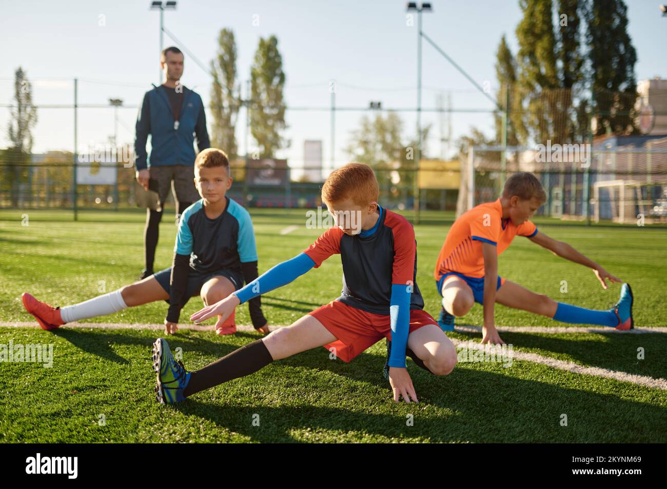 Young boys football players doing warm up workout stretching legs Stock