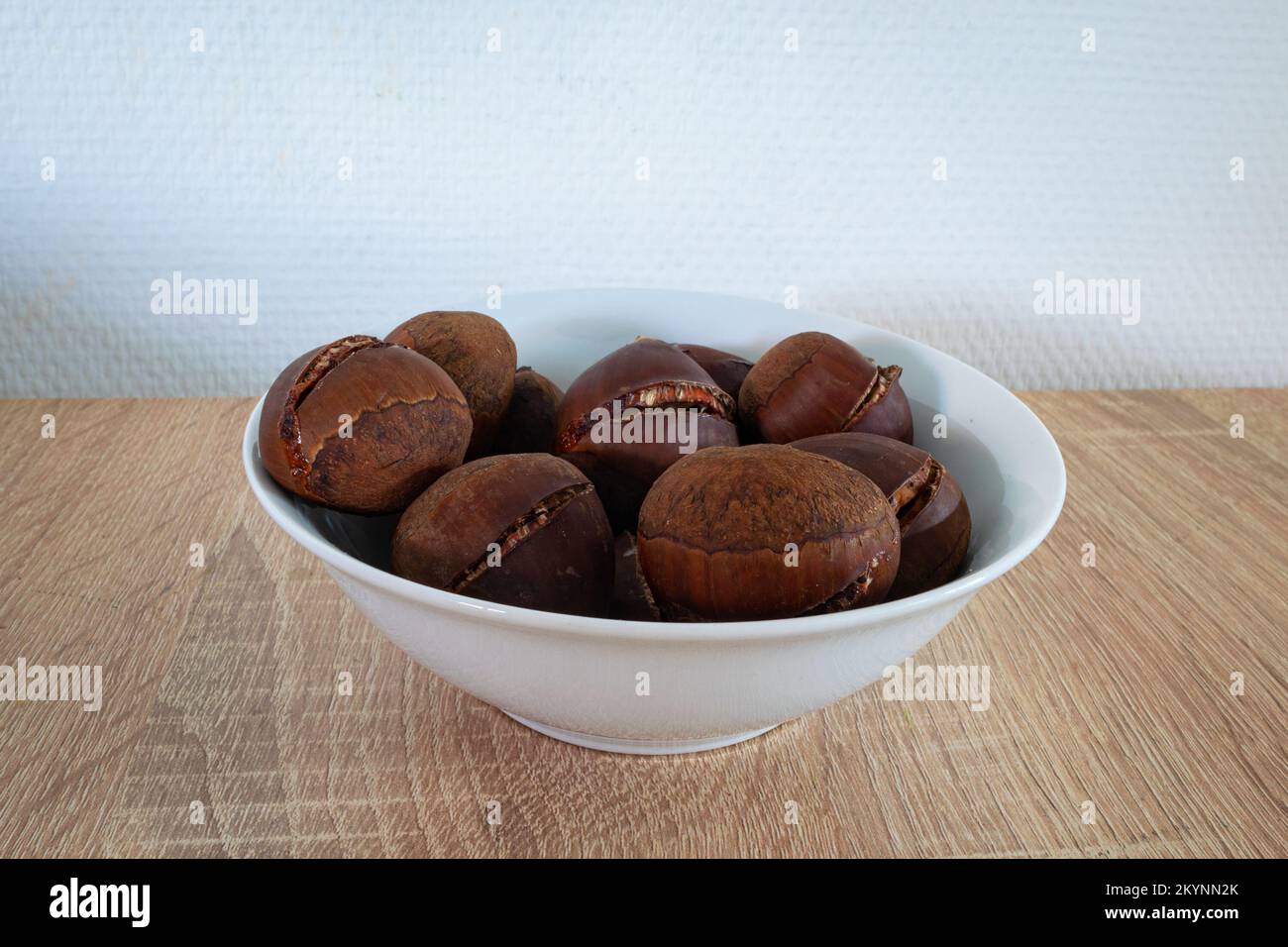 Bowl with roasted sweet chestnuts against a white background Stock Photo