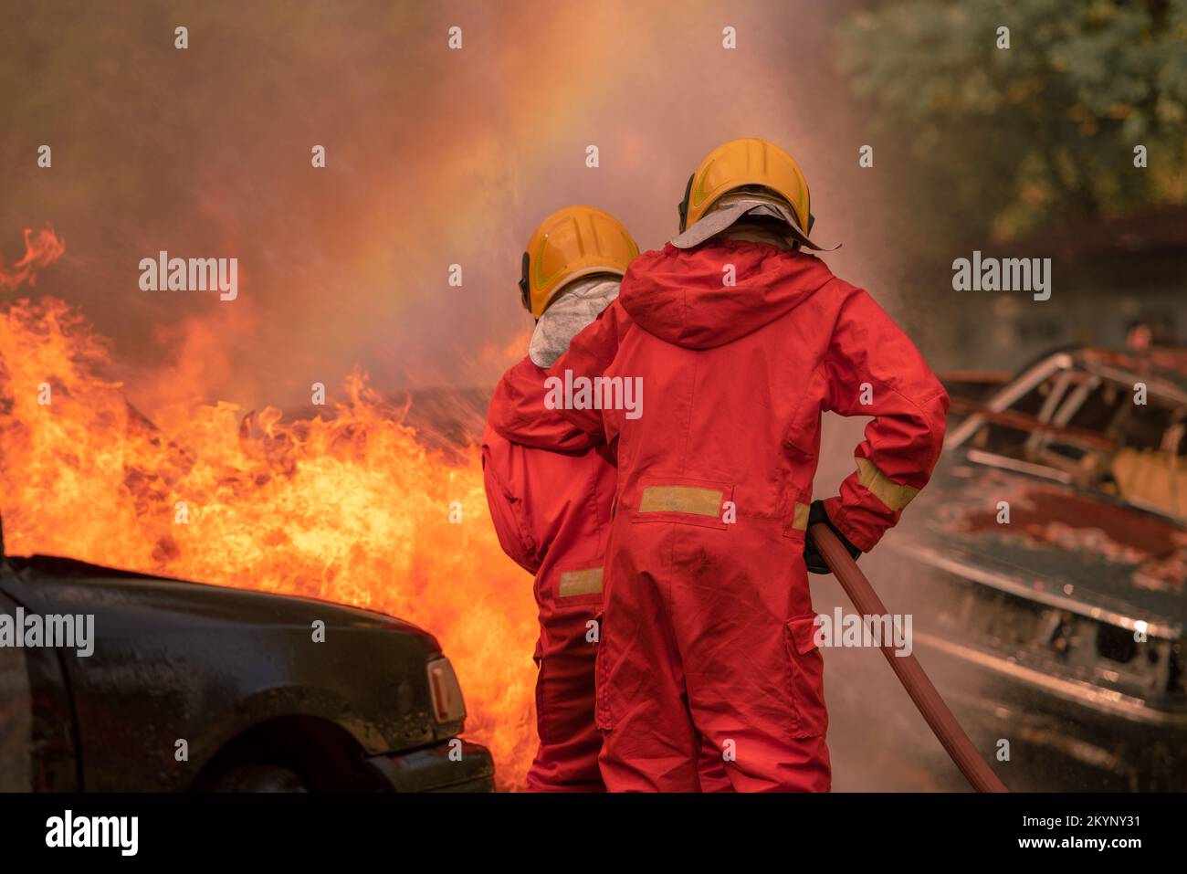 Firefighter Rescue training to stop burning flame, Fireman wear hard hat and safety uniform suit for protection burn using hose with chemical water fo Stock Photo