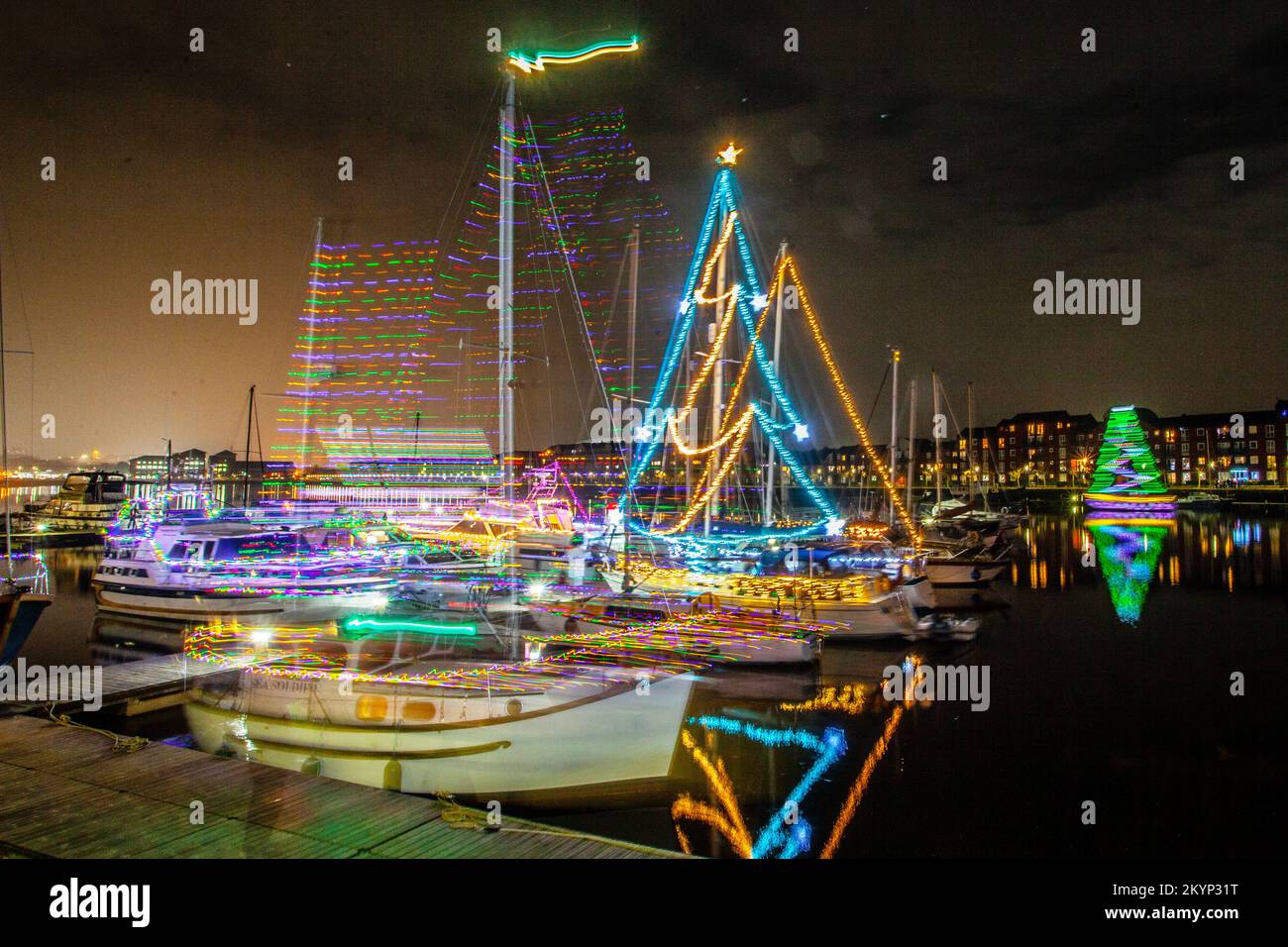 Christmas Lights at Sea. A Bright Holiday Boat Parade in Preston, Lancashire Dec 2022. Moored yachts and sailing boats decorated with sparkling Christmas lights in Preston Marina.  A Christmas night switch on for the crowds lining the dock wall as berth holders light up their boats and enjoy an evening sail under Festive Lights. Stock Photo