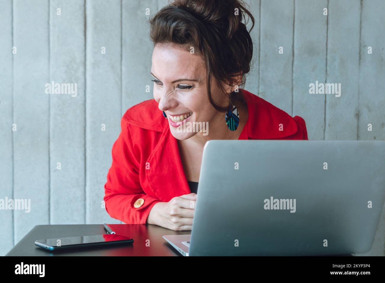 French Caucasian adult business woman, very amused laughing out loud in front of the computer while working online, sitting in a coffee shop. Stock Photo