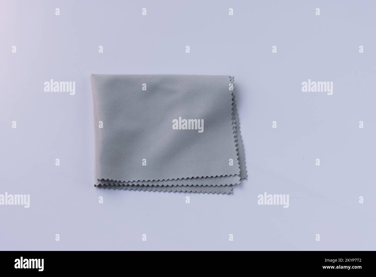 Grey micro fibre cloth. Microfiber cleaning cloth for glasses, eyeglass or camera lens on white background. Stock Photo