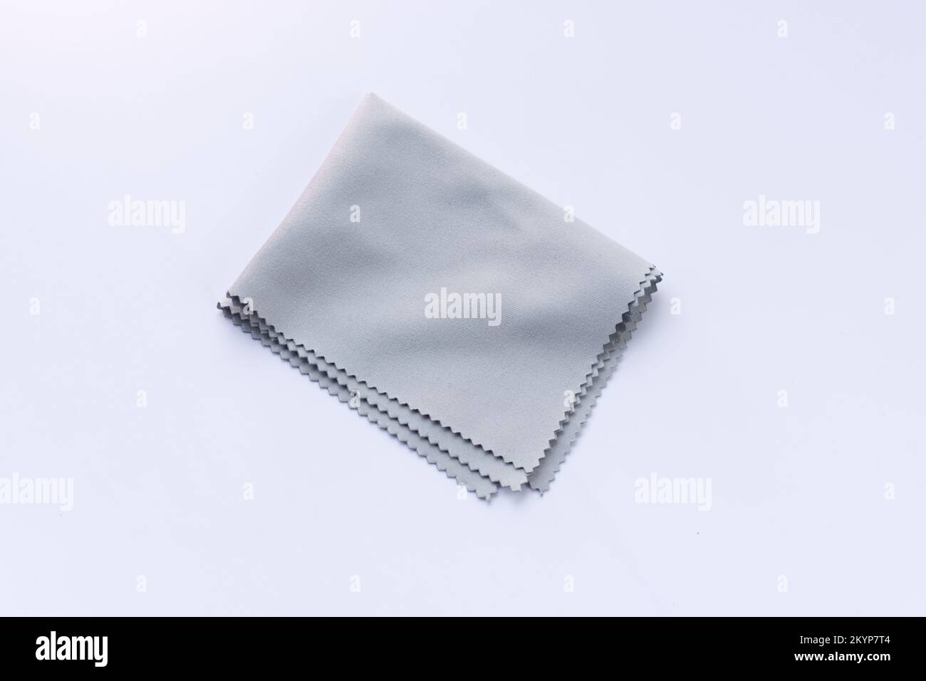 Grey micro fibre cloth. Microfiber cleaning cloth for glasses, eyeglass or camera lens on white background. Stock Photo