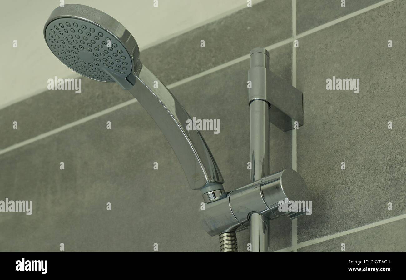 Close up of a shower head and a chrome adjustment bar in the shower