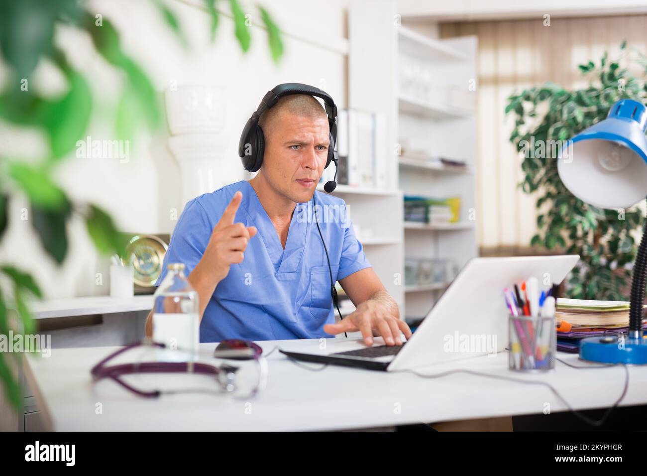Doctor in headphones consults patient using laptop and the Internet ...