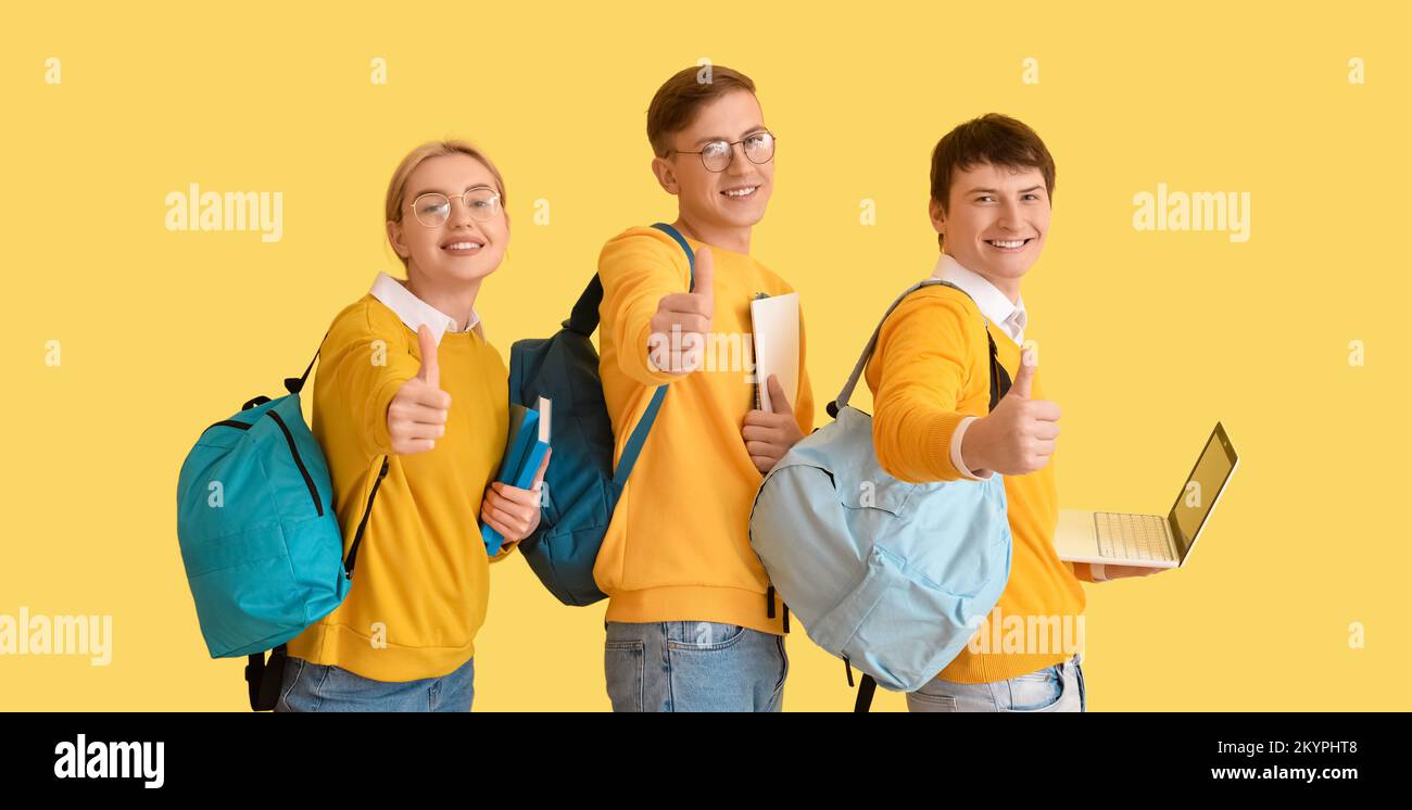 Group of students showing thumb-up on yellow background Stock Photo - Alamy