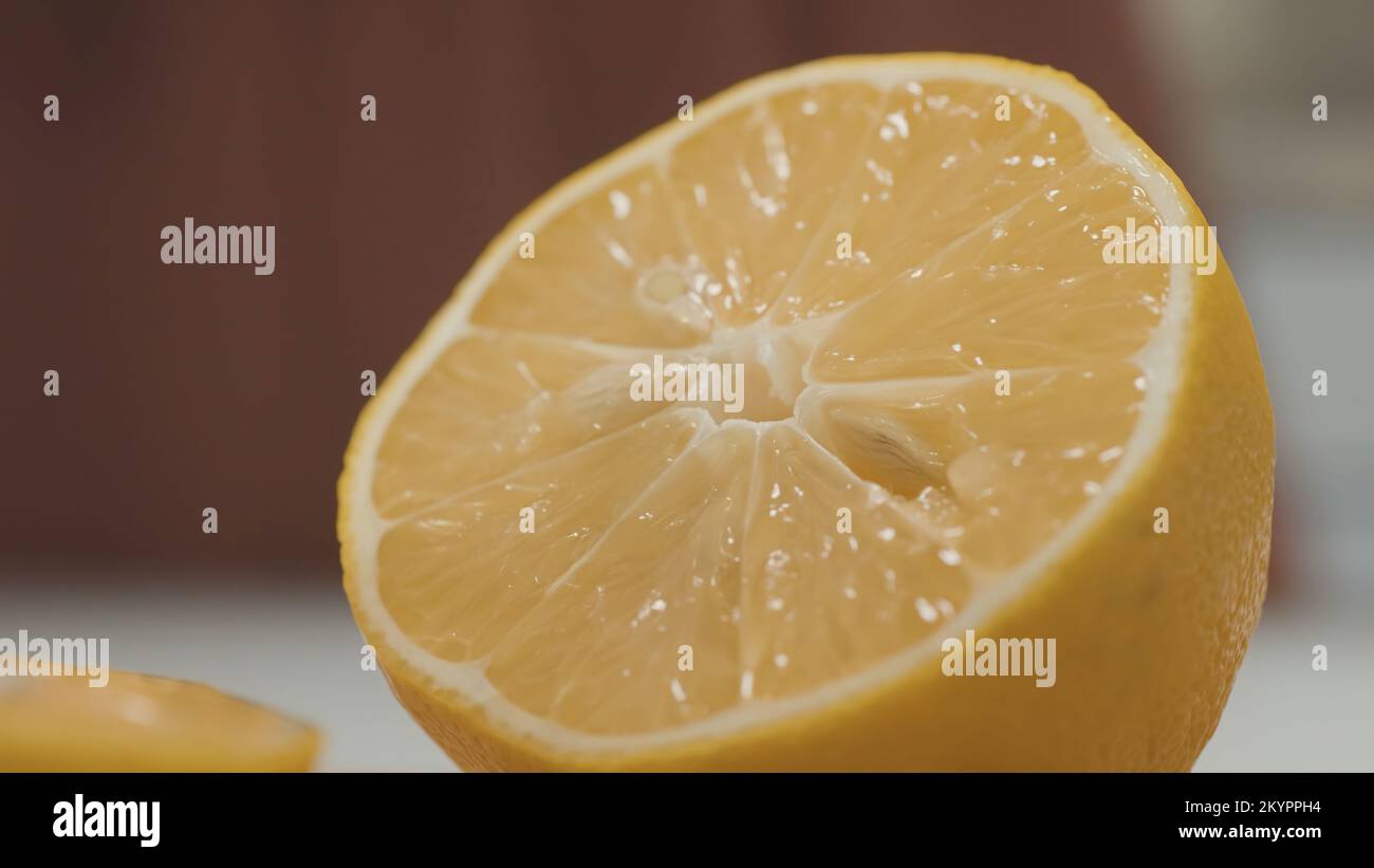 Close-up of sliced juicy lemon. Action. Half fresh juicy lemon is in kitchen. Half lemon to add sourness to dish. Ingredient in form of fresh sour lem Stock Photo