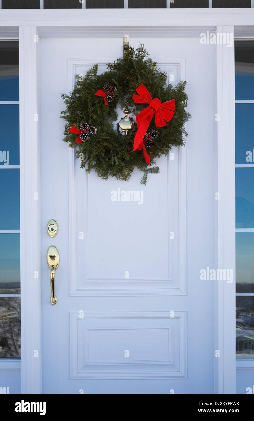 White front entrance door of a country home decorated with a Christmas wreath. Stock Photo