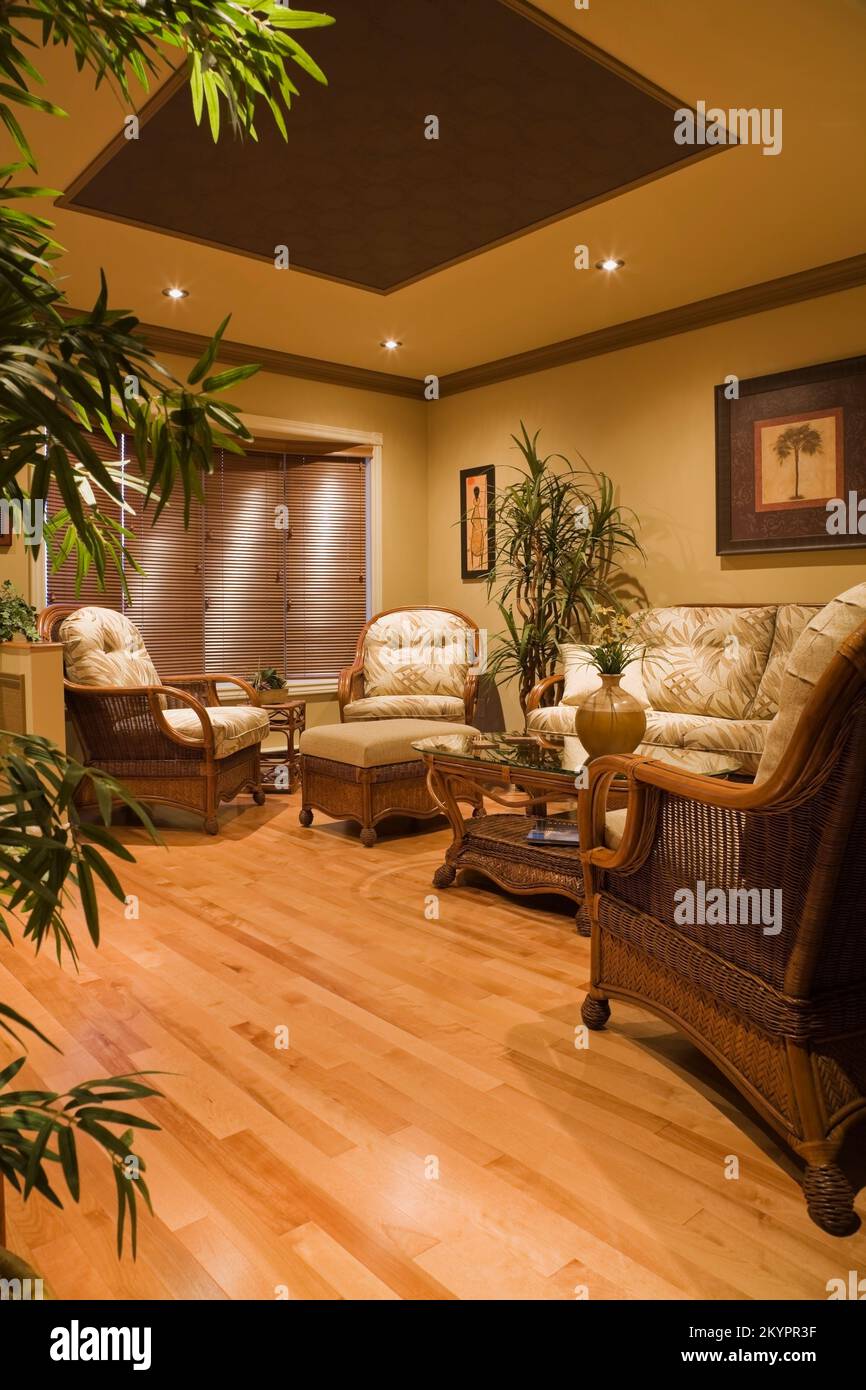 Wicker armchairs and glass top coffee table in living room inside  small bungalow style home. Stock Photo