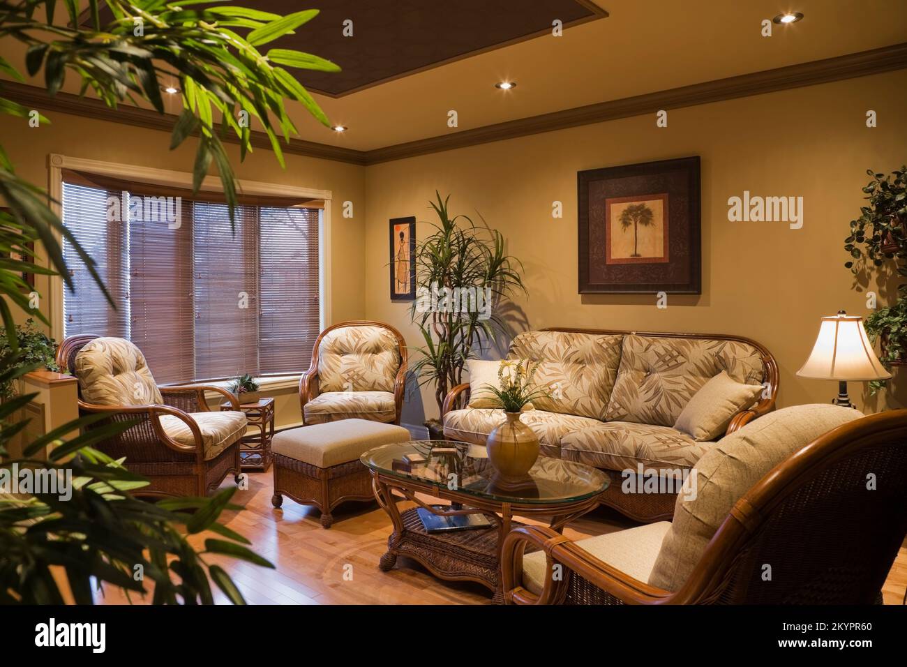 Wicker armchairs, sofa and glass top coffee table in living room inside small bungalow style home, Quebec, Canada. This image is property released. PR Stock Photo