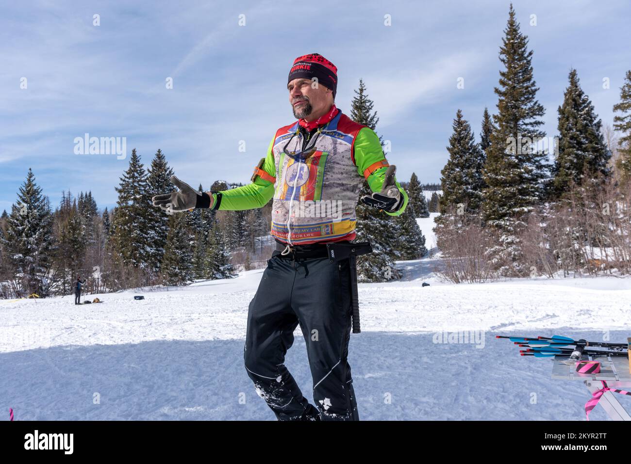 Happy middle aged man in insulated ski wear, arms lifted, walking in snow during Chama Chile Ski Classic in San Juan Mountains near Chama, New Mexico. Stock Photo