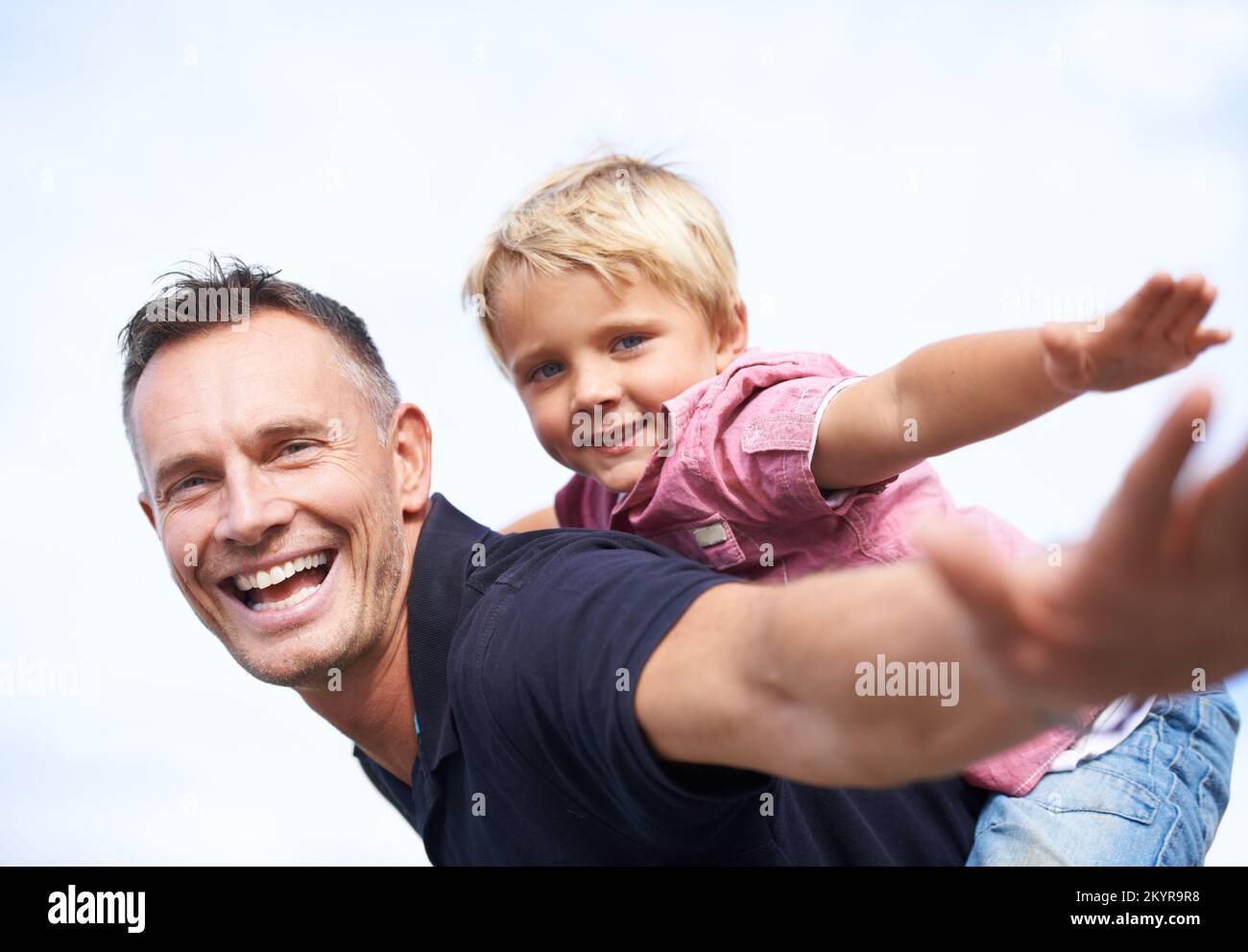 Giving his son wings. a smiling father giving his son a piggyback outside. Stock Photo