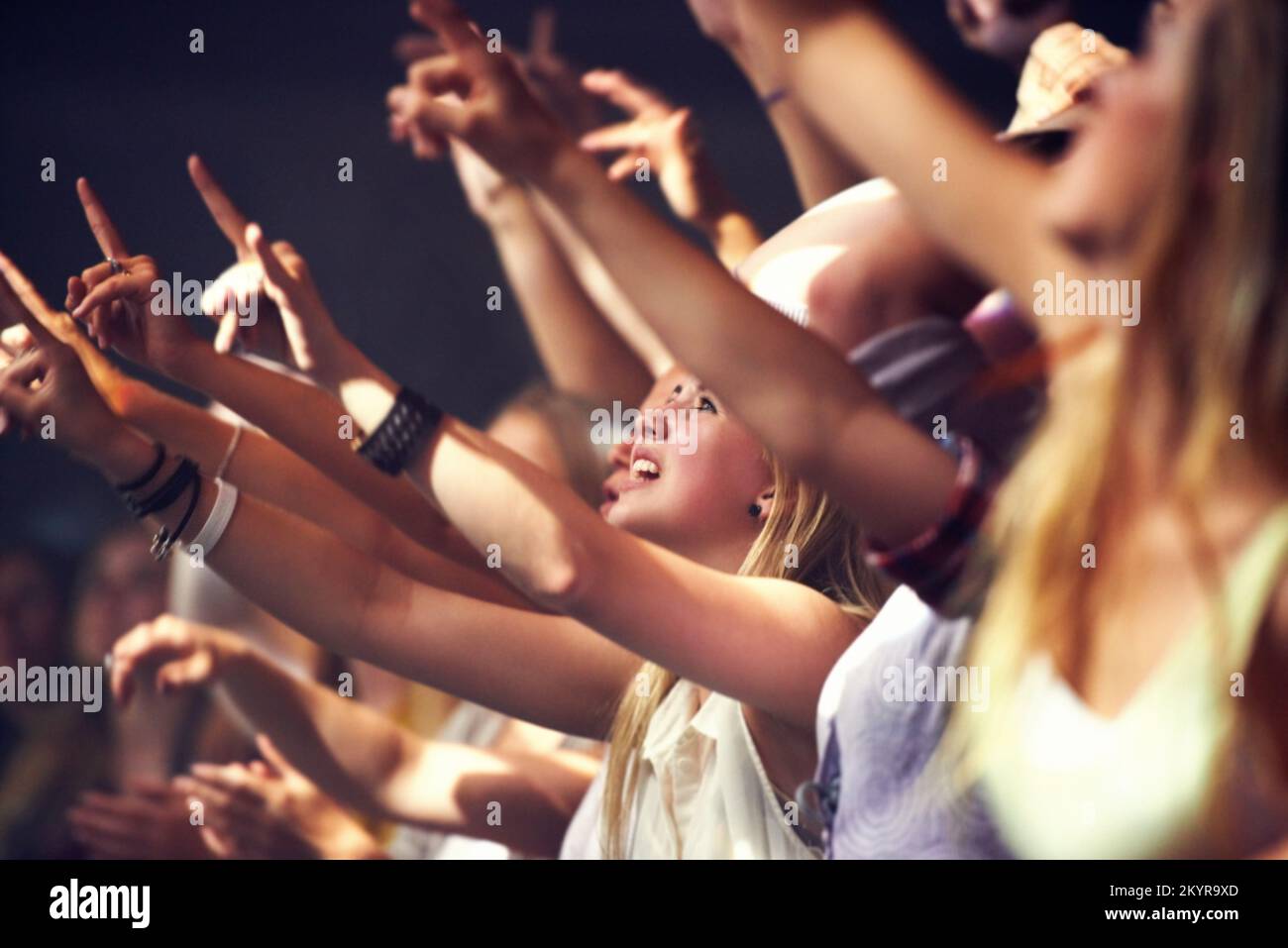 Enjoying the music. A group of people standing with their arms raised at a concert. Stock Photo