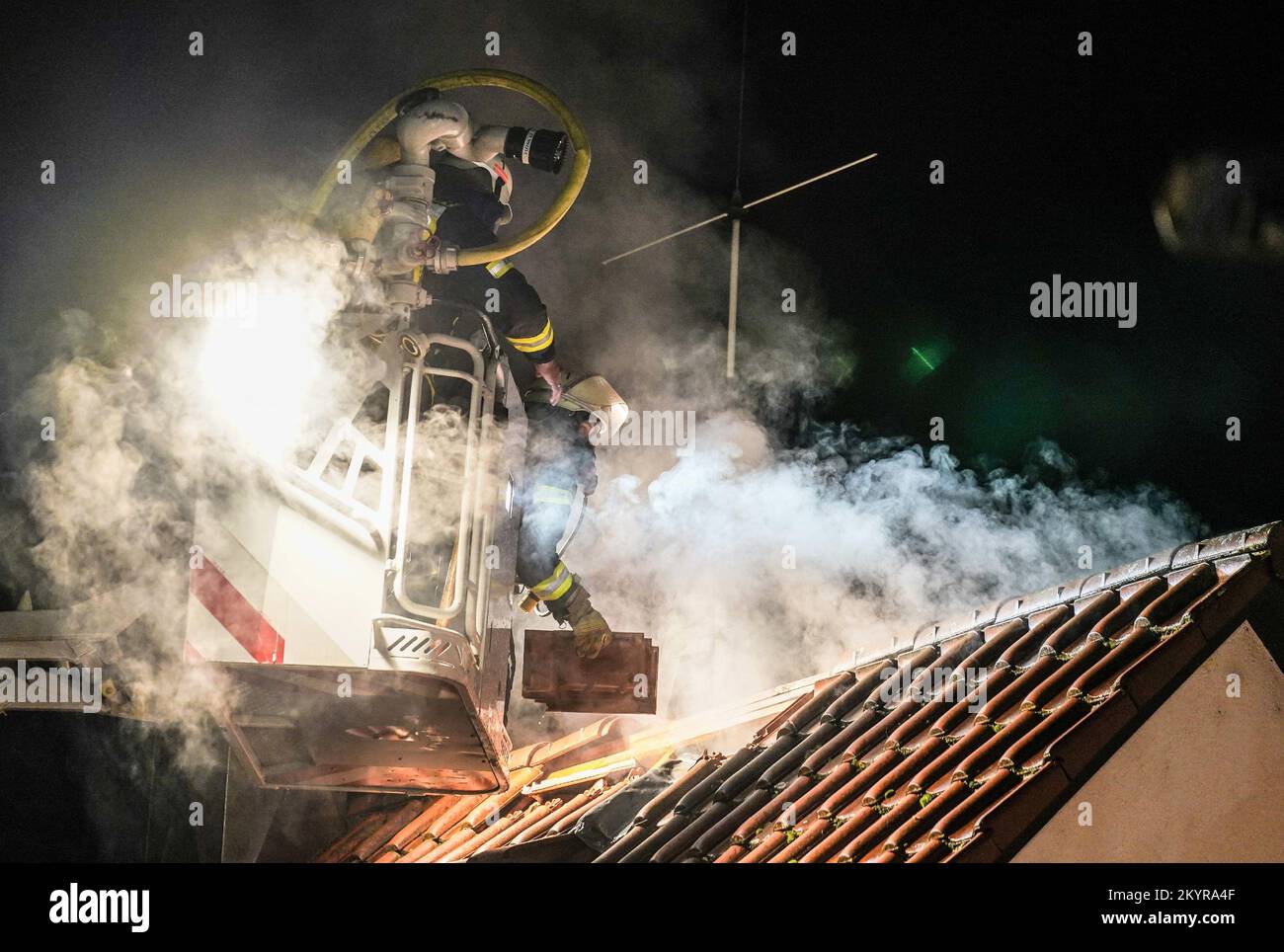 Urbach, Germany. 01st Dec, 2022. Firefighters extinguish a fire from a turntable ladder. A fire in the family house caused damage of about 400 000 euros. The 56-year-old homeowner had placed a pot with hot ashes on the terrace on Thursday evening. According to the report, the pot had ignited and started a fire that spread to the facade, the house entrance and finally the attic. (to dpa: 'Pot with hot ash on balcony: residential building burns down') Credit: Kohls/SDMG/dpa/Alamy Live News Stock Photo