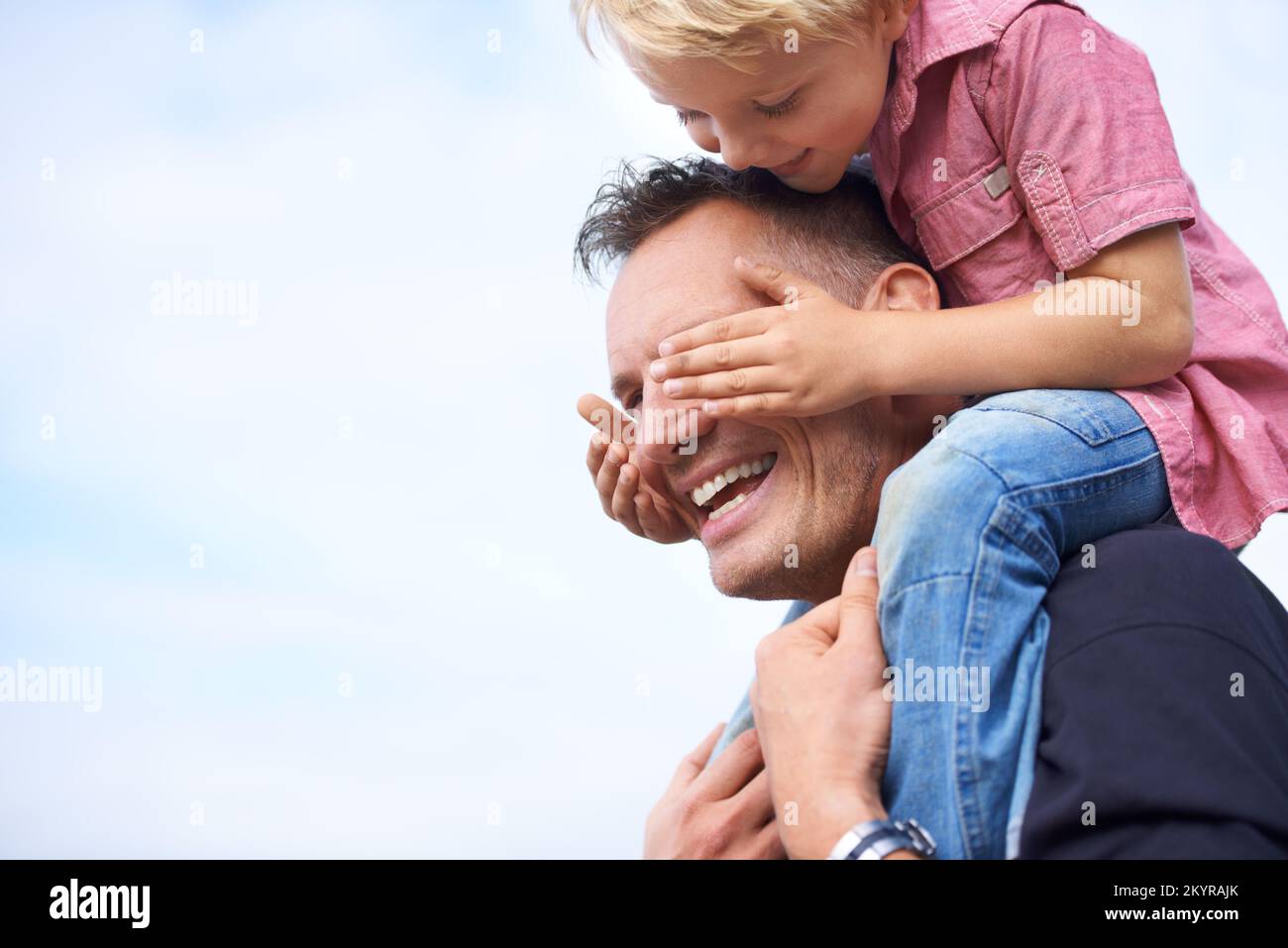 Youll never guess who. a playful father giving his son a piggyback outside. Stock Photo