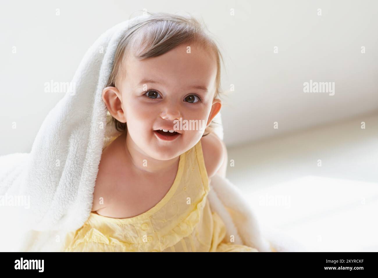 Shes always laughing. a cute little baby girl sitting on the floor playing with her blanket. Stock Photo