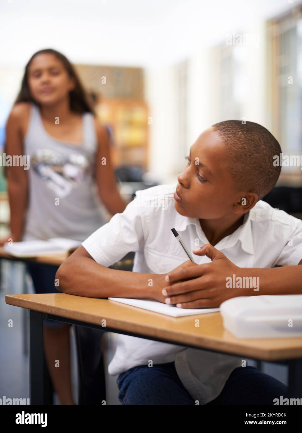 Stop copying me. A young boy writing a test while a classmate tries to copy. Stock Photo