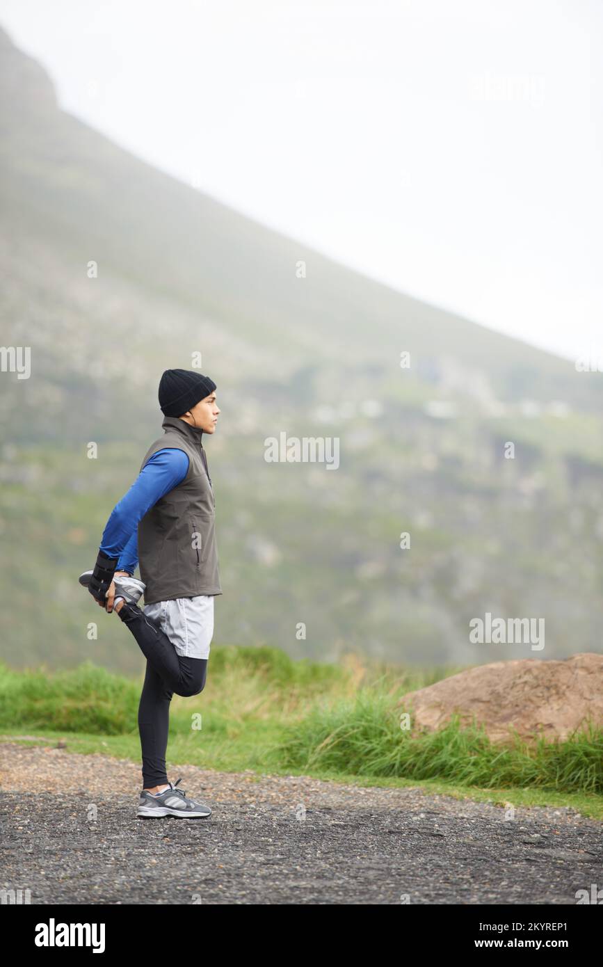 Breathing in the fresh air...Full length of a young jogger stretching in the morning and admiring the view. Stock Photo