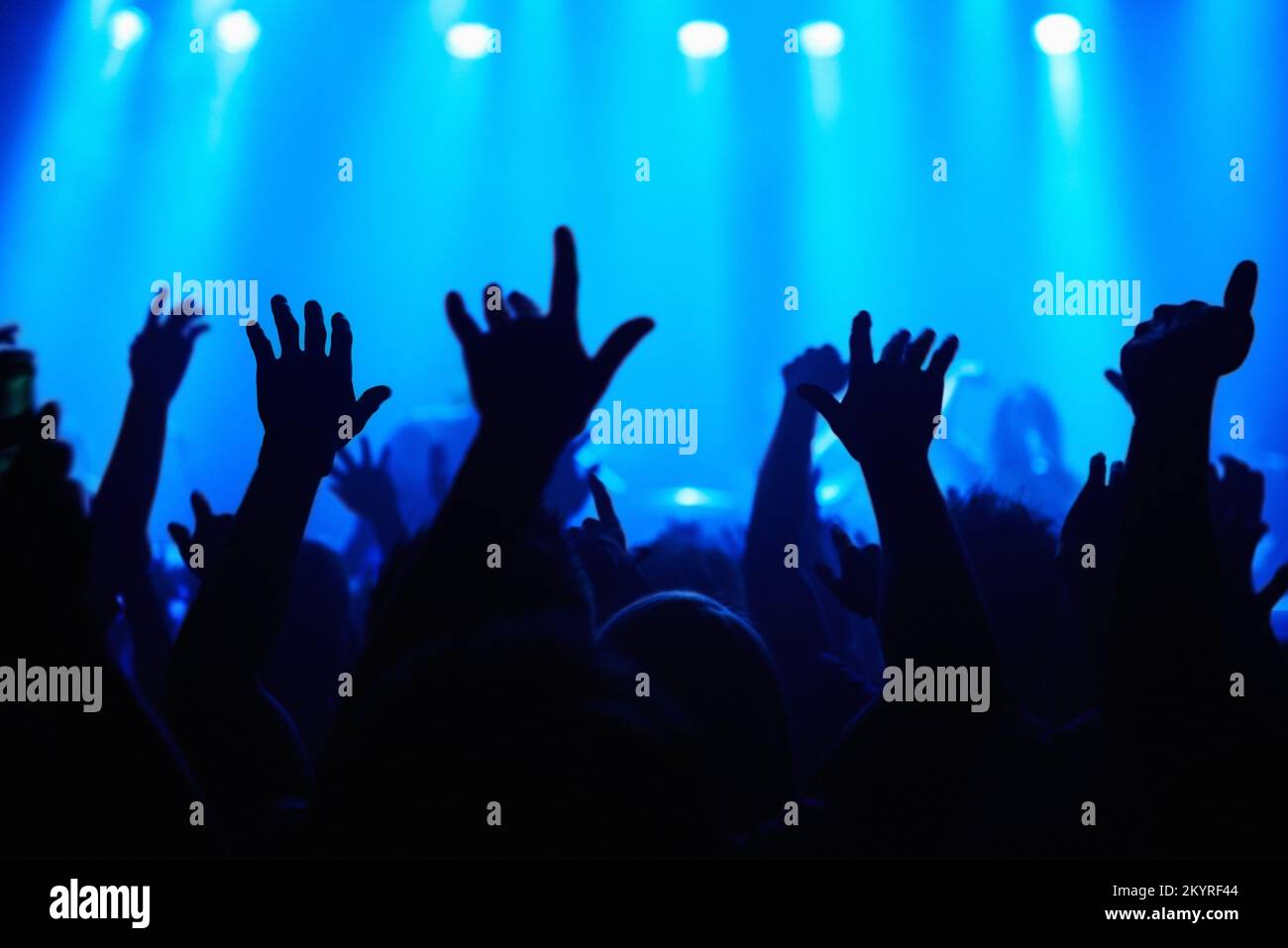 Music brings us together. A crowd of people watching a band play on stage at a nightclub. Stock Photo