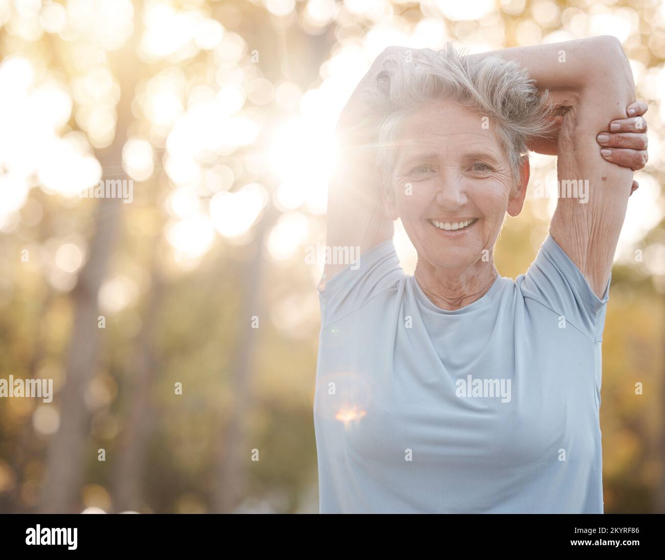 Fitness, nature and senior woman stretching before an outdoor run or cardio workout with bokeh. Happy, smile and portrait of elderly lady doing warm Stock Photo