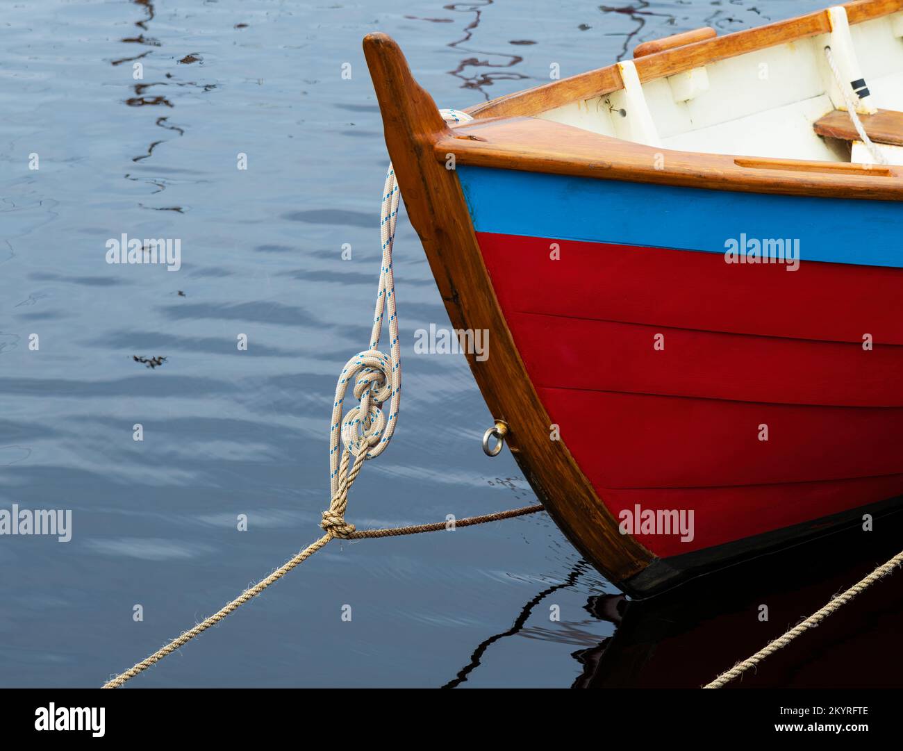 Clinker built boat painted red and blue and tied up with one of many nautical knots. Stock Photo
