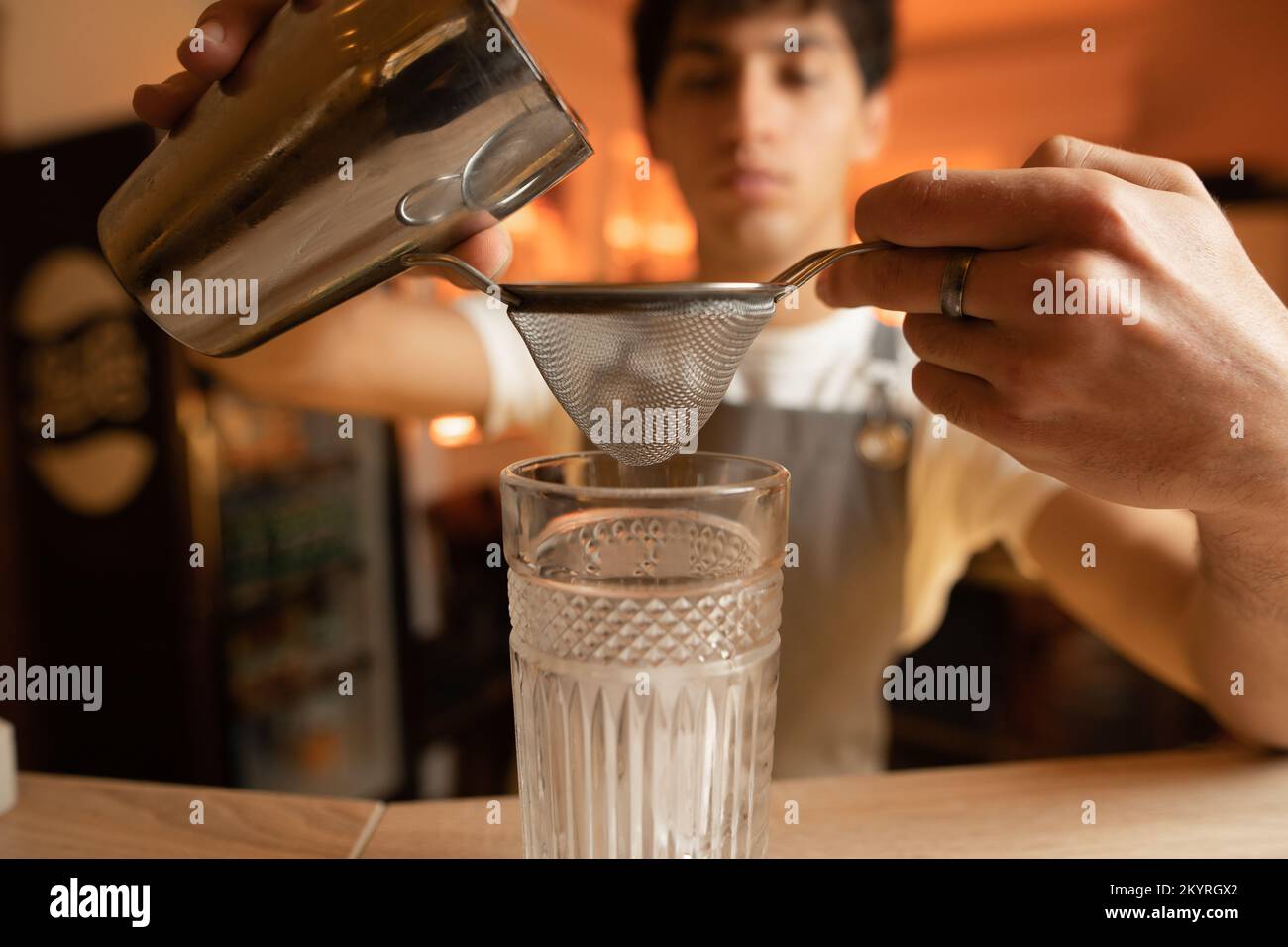 Bartender preparing a cocktail pouring from a shaker filters using a