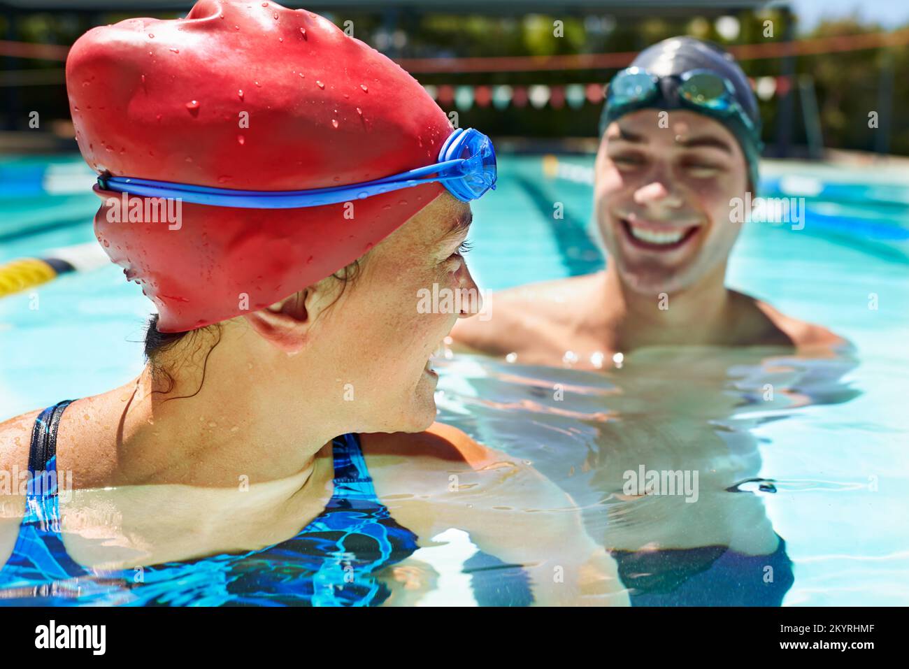 Friendly competition. Two swimmers standing in a pool smiling at each