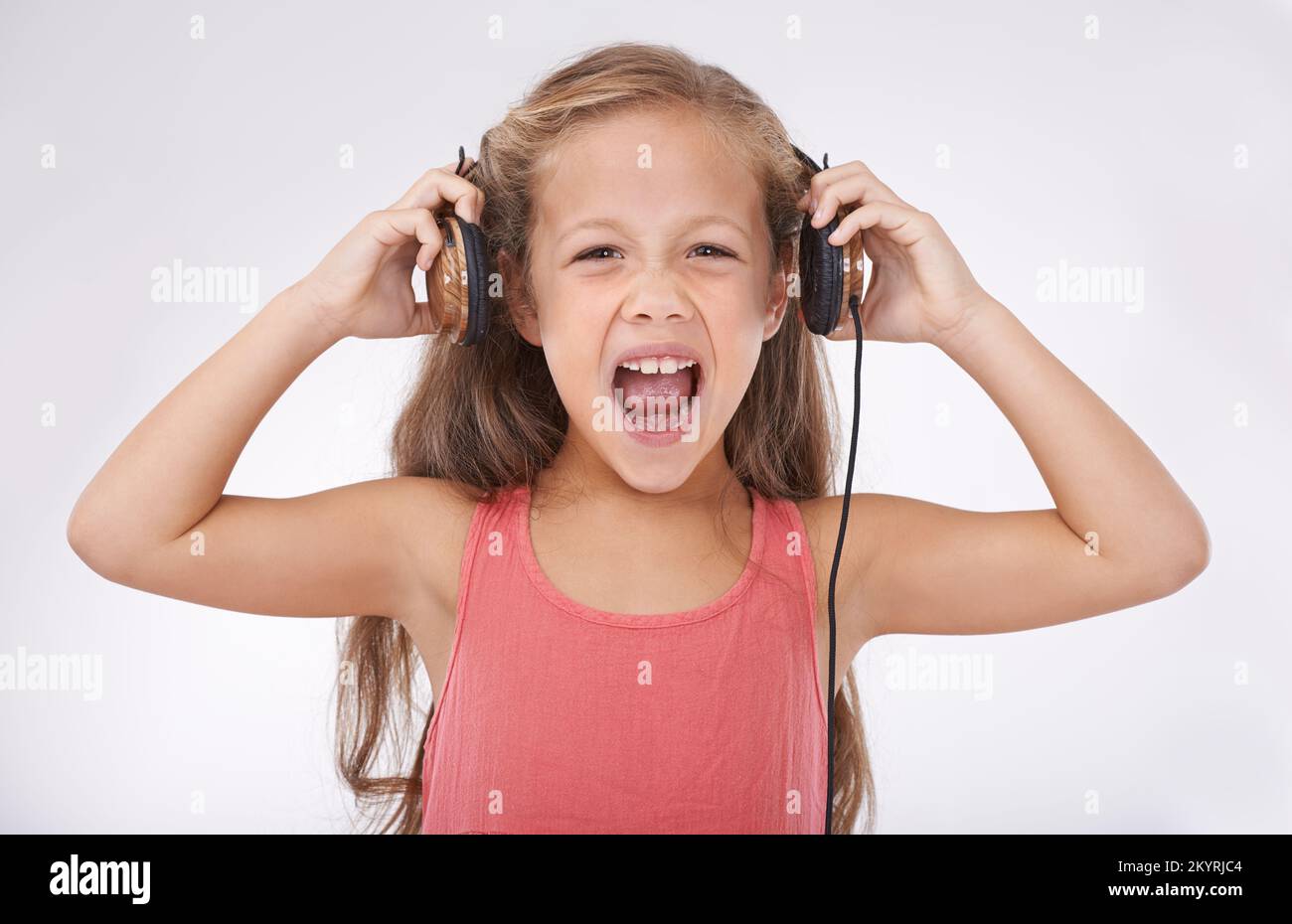 Feel the noise. A young girl screaming while wearing a pair of headphones. Stock Photo