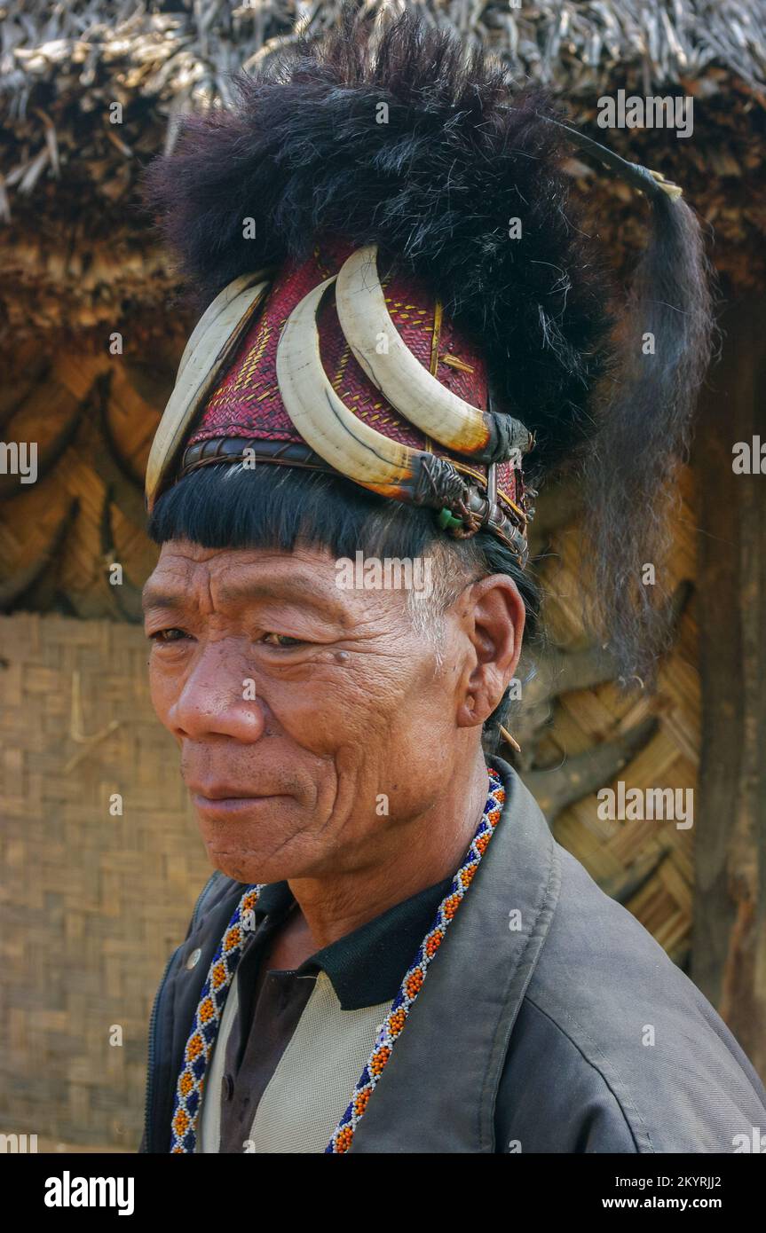 Mon, Nagaland, India - 02 28 2013 : Portrait of Naga Konyak tribe man with typical hair style wearing traditional red cane hat with boar tusks and fur Stock Photo