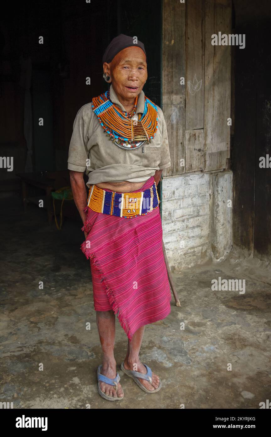 Mon, Nagaland, India - 03 03 2009 : Portrait of standing old Naga Konyak tribe woman wearing traditional necklace, belt, earrings and black head scarf Stock Photo