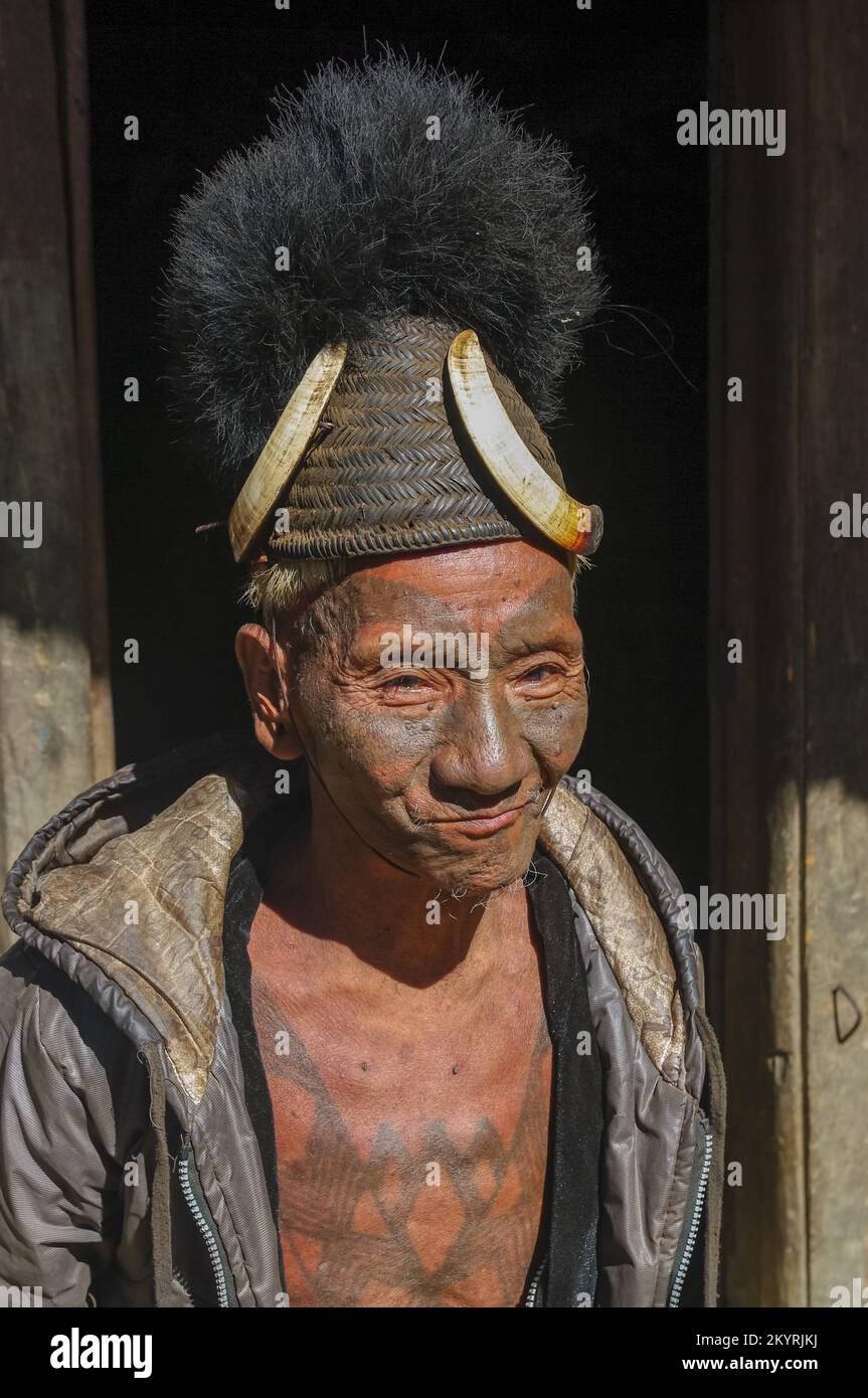 Mon, Nagaland, India - 11 25 2013 : Portrait of old Naga tribe head hunter warrior with traditional facial and chest tattoo wearing Konyak hat Stock Photo