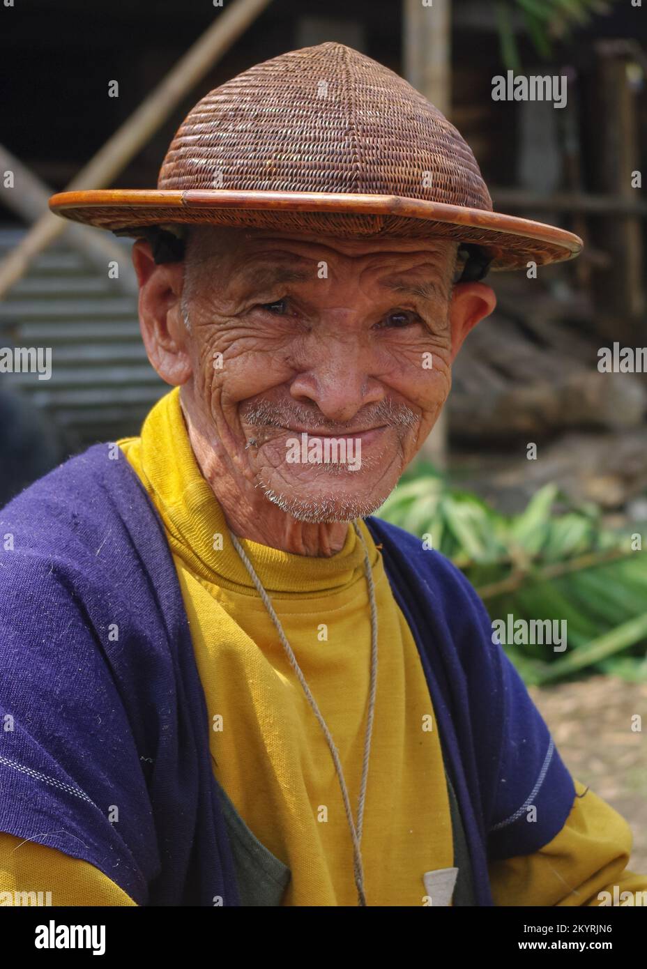 West Siang, Arunachal Pradesh, India - 03 06 2014 : Portrait of smiling old Adi Galong or Galo tribe man wearing traditional boat shaped cane hat Stock Photo