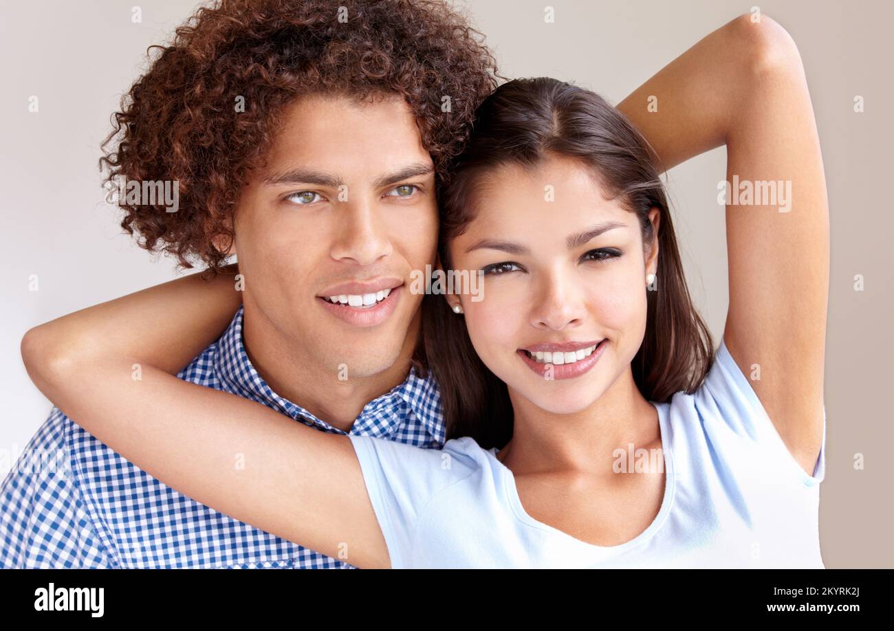 Young love. Studio shot of a happy young ethnic couple holding each other and smiling. Stock Photo