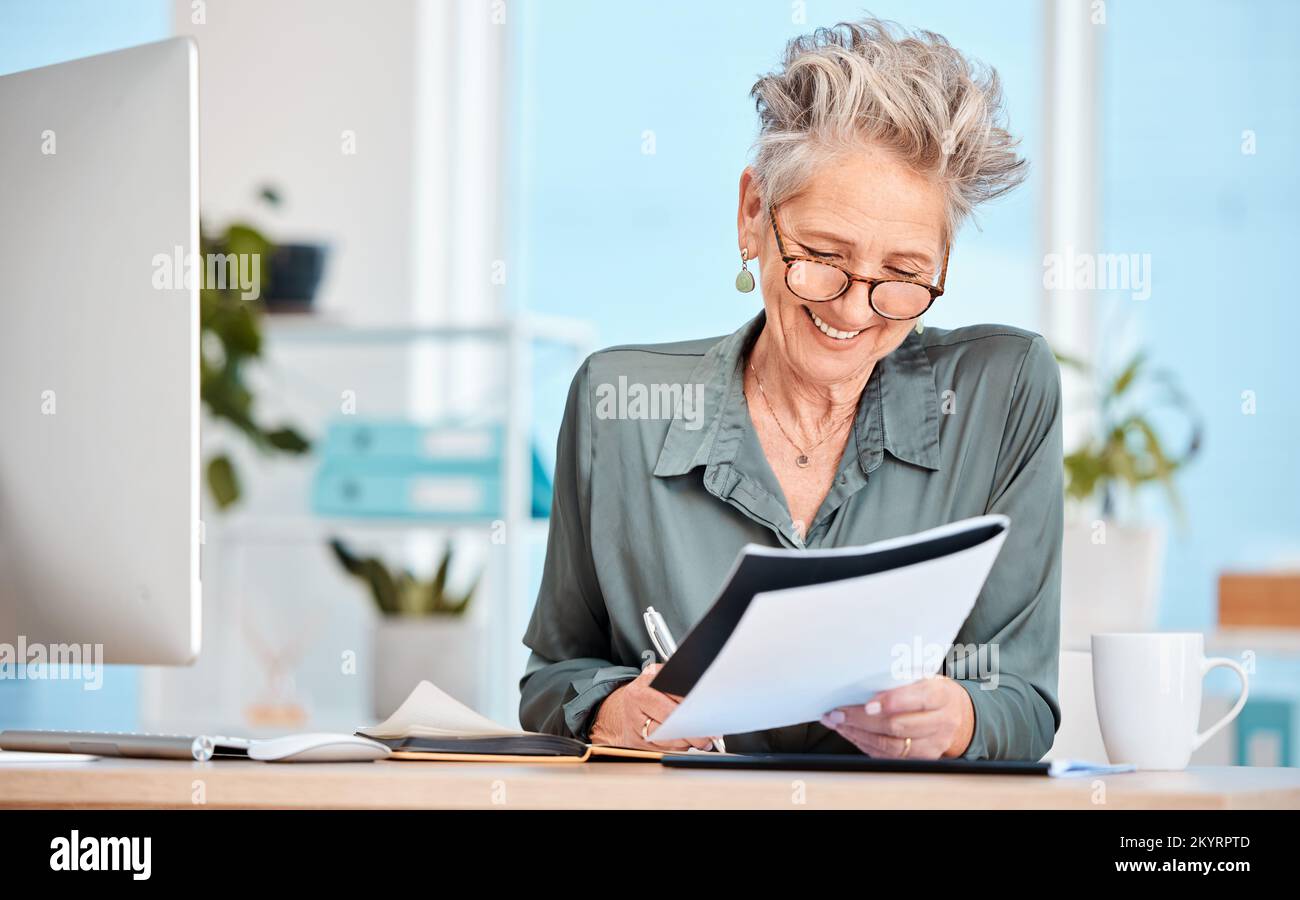 Finance paper, working and business woman writing notes in office, sitting at desk. Ideas, vision or senior woman with pen in hand to write, smile or Stock Photo