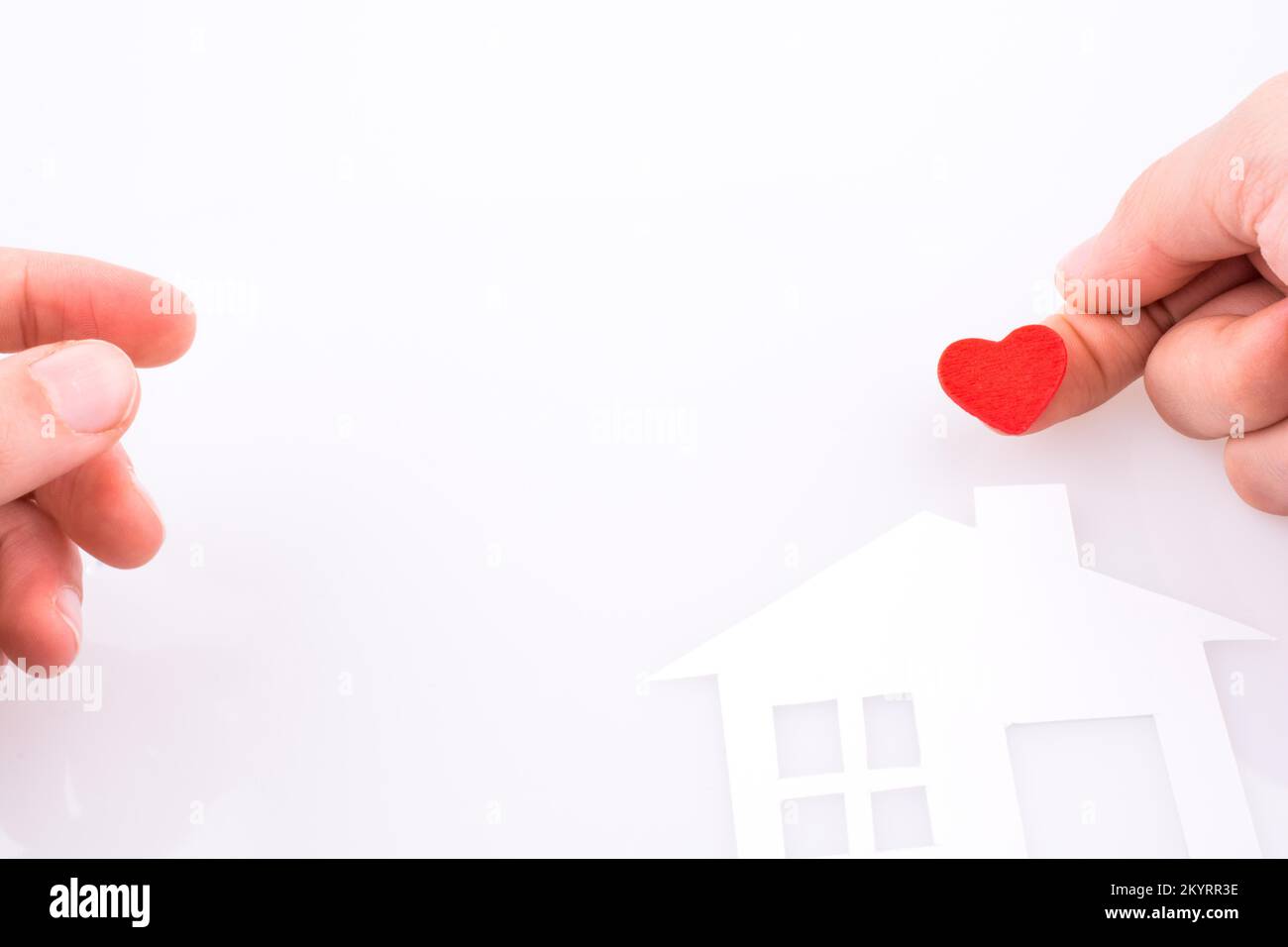 Paper house and heart shape in hand on a white background Stock Photo ...