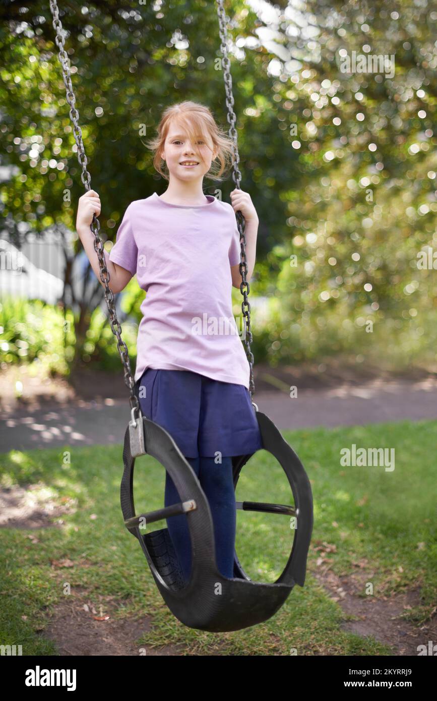 Want to see how high Ill go. Cute little girl standing on a swing in a