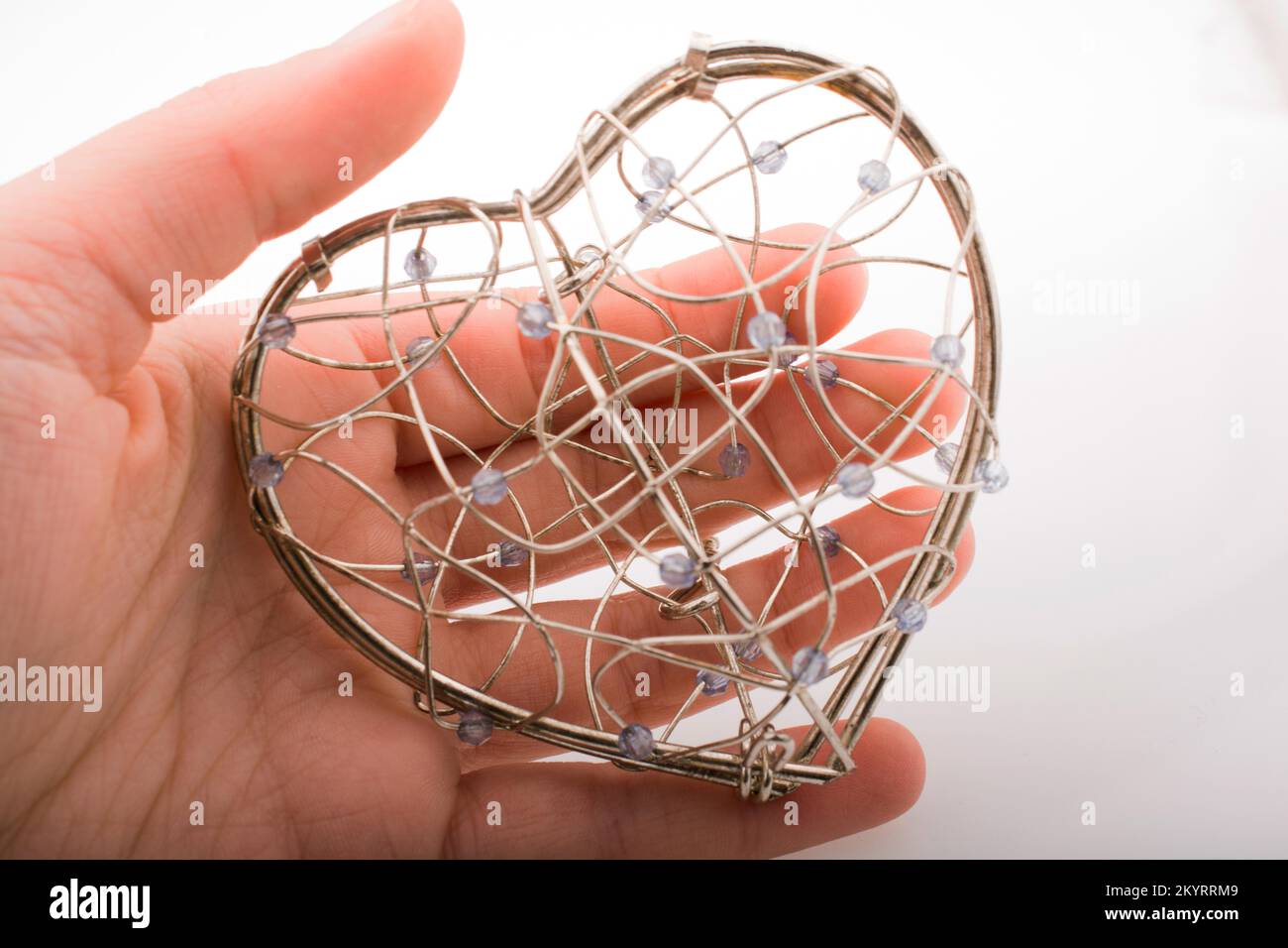 Hand holding heart shaped cage on a white background Stock Photo - Alamy